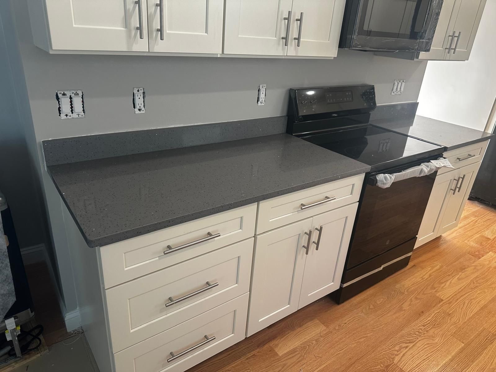 Bright kitchen with white cabinetry and a stylish black countertop, highlighting Marble and Granite Services